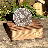 Photo of silver cardinal sobriety coin on wooden display stand with text and bird design