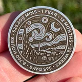 Photo of silver sobriety coin with Starry Night design held in hand, showing text around edge reading "1 YEAR" and other recovery milestone details